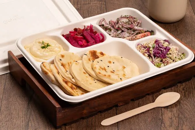 A tray of flatbreads, hummus and salads
